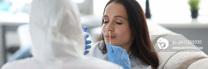 Medical officer in protective suit takes biological material from woman with shelf in her mouth. Delivery of analysis to determine the coronavirus concept