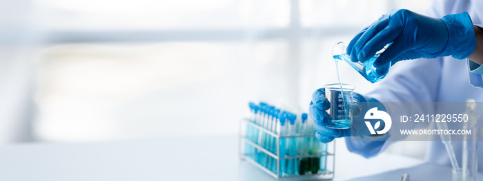 Lab assistant, a medical scientist, a chemistry researcher holds a glass tube through the blood sample, does a chemical experiment and examines a patient’s blood sample. Medicine and research concept.