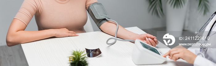 partial view of doctor measuring blood pressure of pregnant woman near ultrasound scan on desk, banner