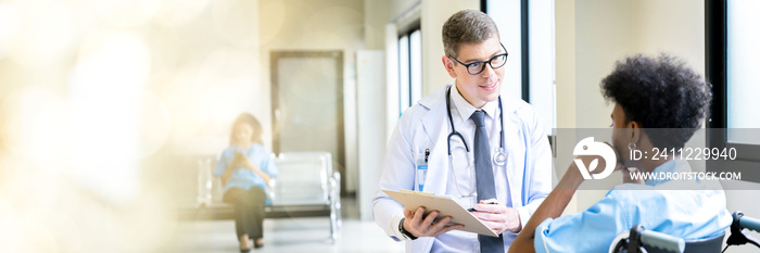 Web banner A male doctor takes a male patient who is admitted at the hospital for a walk through the window corridors of the hospital for psychotherapy. by having the patient sit in a wheelchair