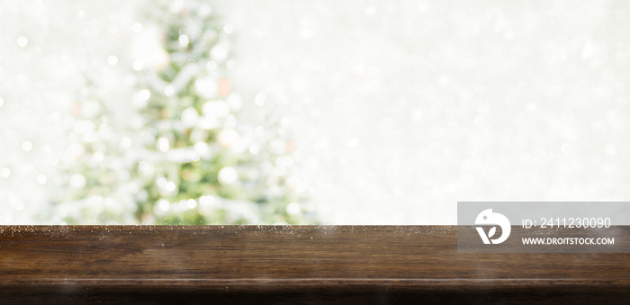 Empty dark brown wooden table top with abstract muted blur christmas tree and snow fall background w