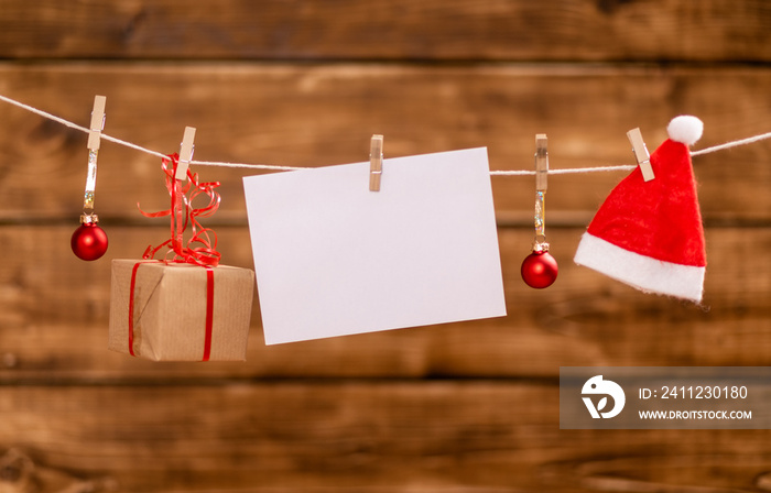 Nicholas hat, christmas balls, present and a note with copy space hang on a rope