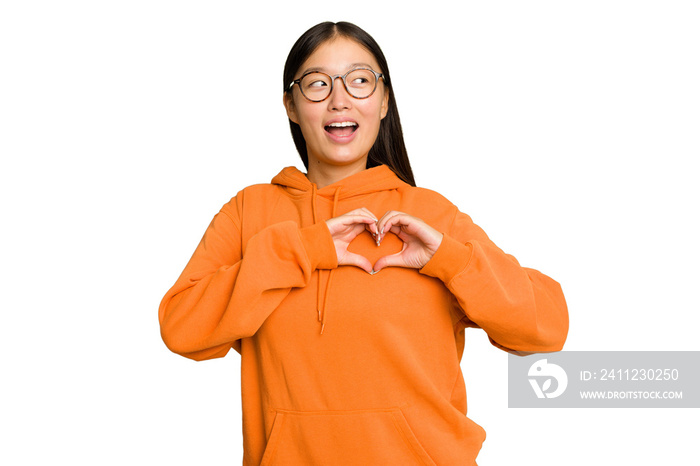 Young Asian woman isolated on green chroma background smiling and showing a heart shape with hands.