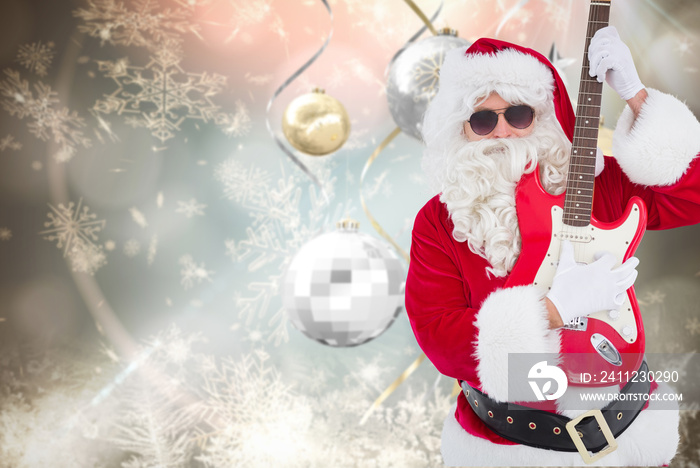 Santa with sunglasses playing electric guitar against hanging christmas decorations