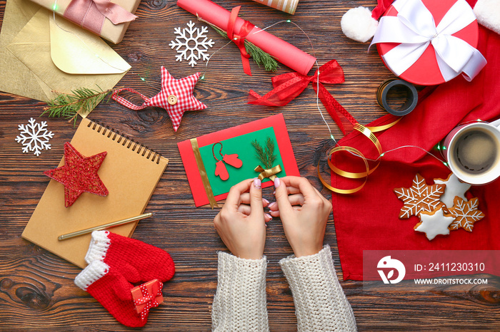 Woman decorating Christmas card  at wooden table