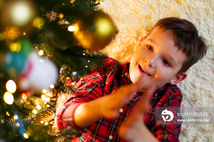 Little cute child decorating the Christmas tree on Christmas Eve at home