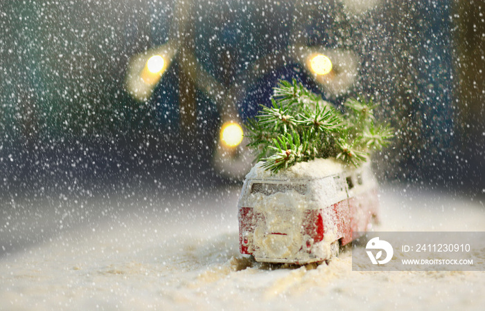 Christmas card with little vintage bus with christmas tree on the roof. Car sneaks through the snowf