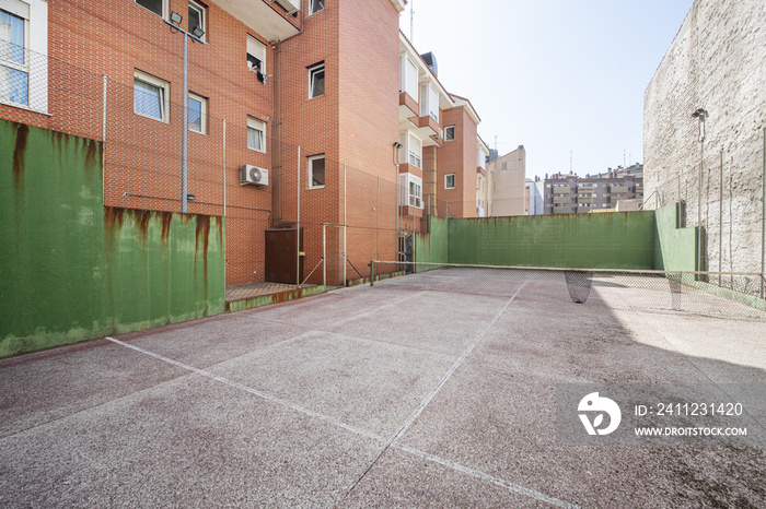 An urban tennis court in a block courtyard between buildings