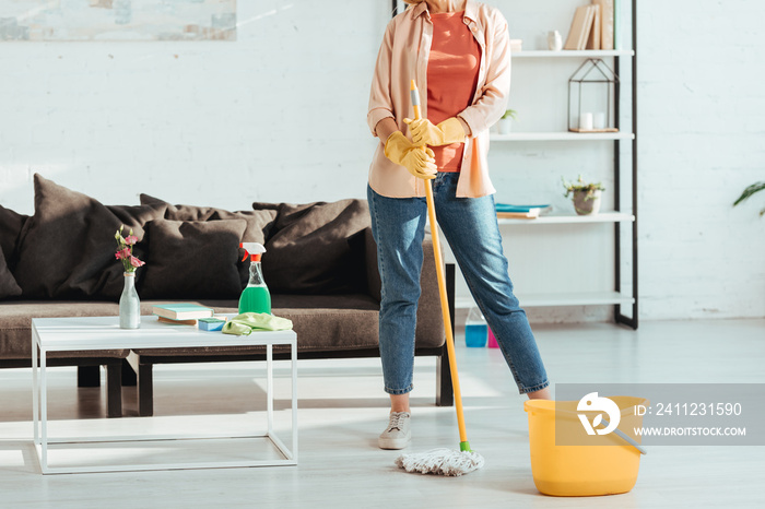 Cropped view of woman cleaning house with mop and bucket