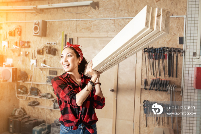 Asian woman worker carrying a wooden boards at the shoulder, the concept of blue collar workers and 