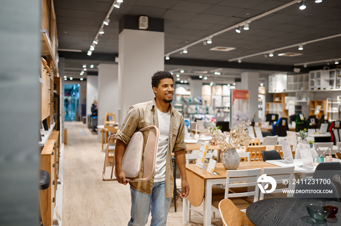 Man carrying folding chair to shop counter