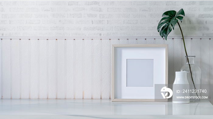 Mockup picture wooden frame and ceramic vase on white marble table in white room, copy space.