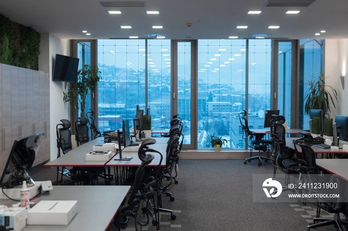 Front view of coworking office interior with workplaces, blank picture frame on wall and computer.