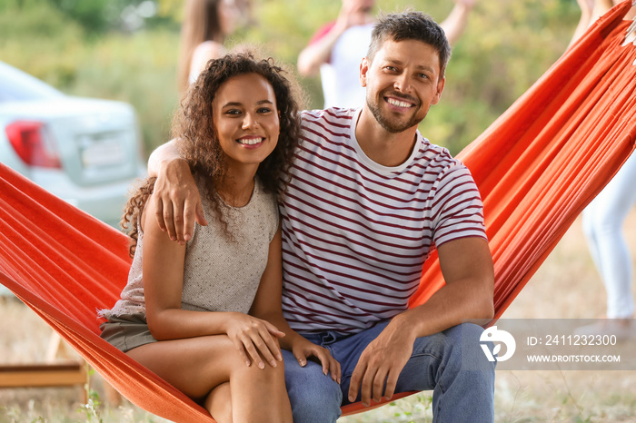 Young couple relaxing in hammock at barbecue party on summer day