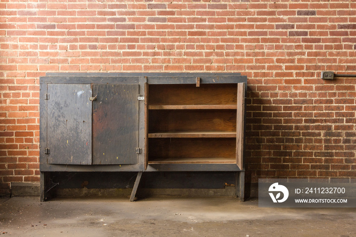 Empty cabinet left forgotten in an abandoned factory with red brick wall