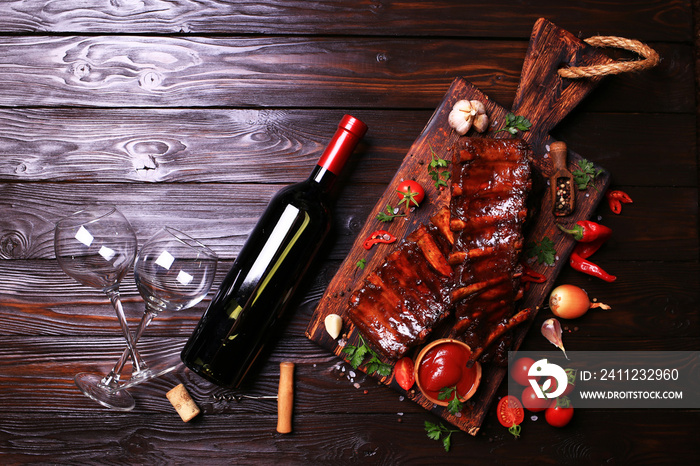 Grilled pork ribs with bottle of red wine spices and vegetables on wooden background