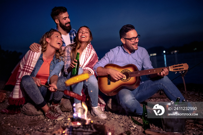 Group of young friends having picnic at night