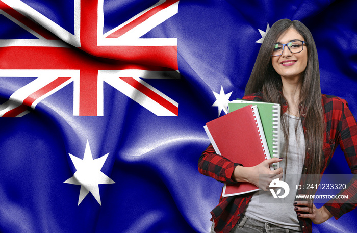 Happy female student holdimg books against national flag of Australia