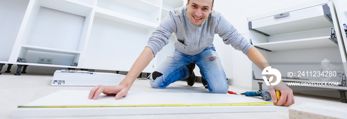 Young man dressed casual assembling furniture in new house