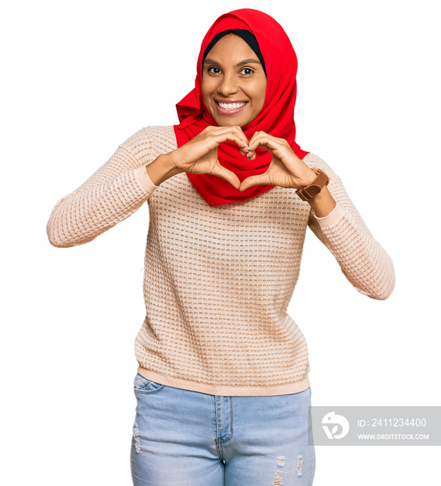 Young african american woman wearing traditional islamic hijab scarf smiling in love doing heart sym