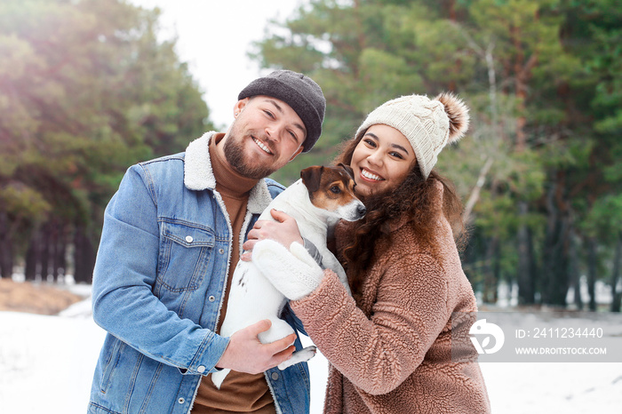 Happy young couple with dog in forest on winter day