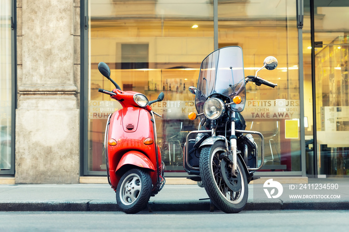 Vintage red scooter and black motorcycle parked on road empty italian city street. Symbol of couple,