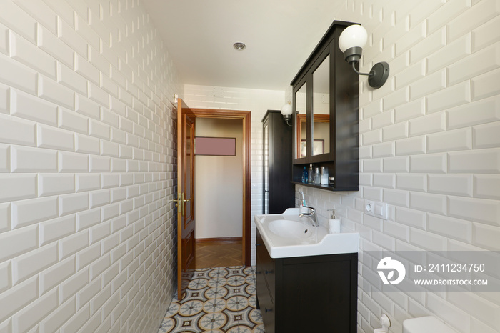 Bathroom with porcelain sink with black wooden cabinet, mirrored cabinet and white tiles on the wall