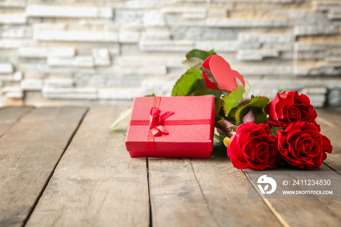 St. Valentines Day concept. Fresh red roses and gift box on wooden table