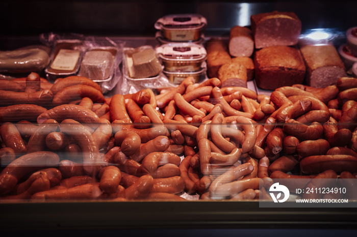 Counter full filled and neatly folded with raw and smoked meat and sausages in butcher shop.