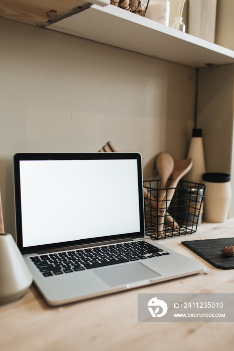 Laptop with blank screen and kitchenware in kitchen. Mockup for cafe, restaurant, magazine.