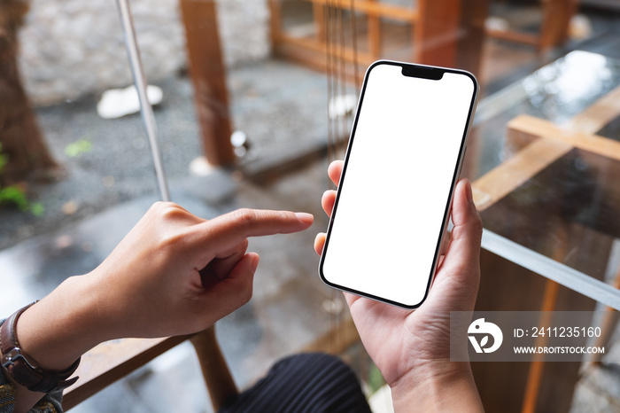 Mockup image of a woman holding and pointing finger at mobile phone with blank white desktop screen 