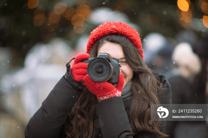 woman photographer with professional camera shooting outdoors at winter time