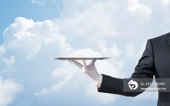 Waiter holding empty silver tray over blue sky