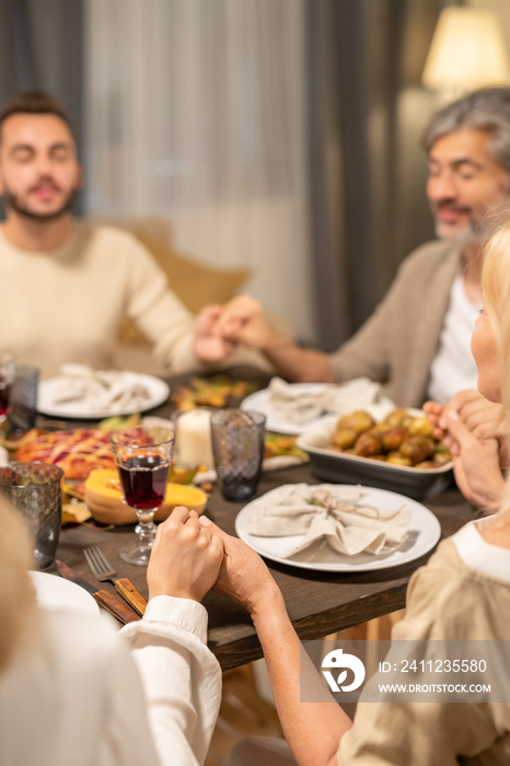 Contemporary family of four praying by served festive table in living-room