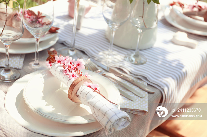 Plate with napkin and branch of flowers on served festive table