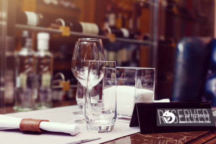 Reserved sign on a table in restaurant. Empty glasses set in restaurant