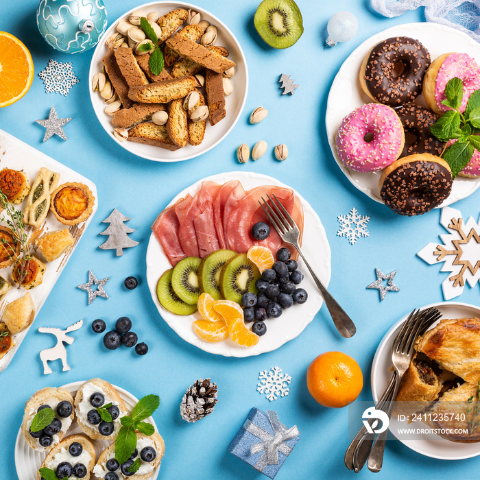 Christmas dinner party table flat lay. Holiday food concept background over blue, top view, overhead