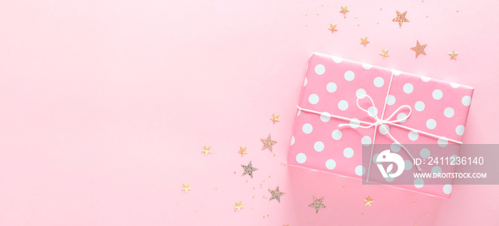 Gift box on a delicate pink background with sparkles, copy space.