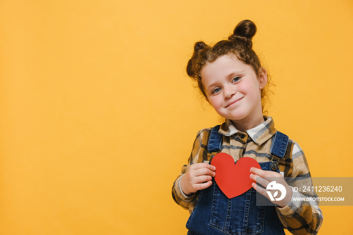 Portrait of positive little sincere adorable child girl holding red heart on chest feeling gratitude