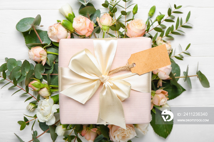 Beautiful flowers and gift on white wooden background