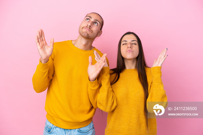 Young caucasian couple isolated on pink background frustrated by a bad situation