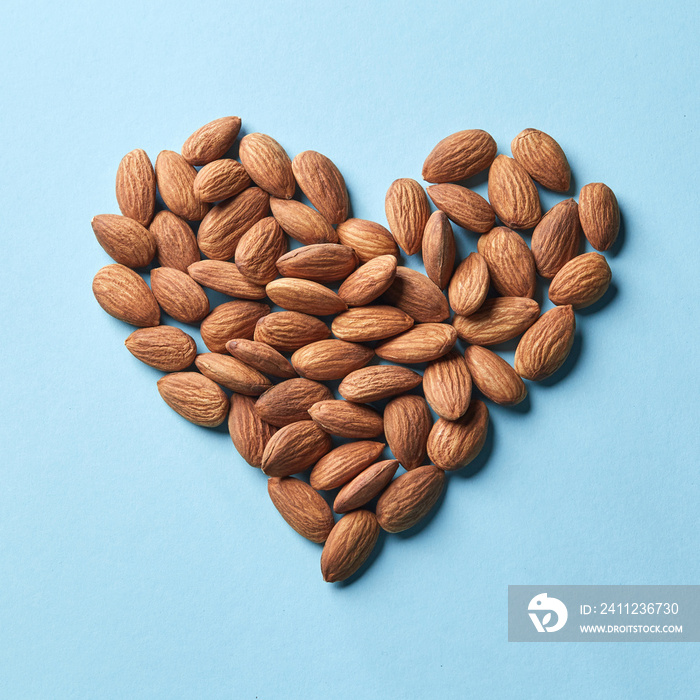 Pattern in the form of heart from almonds on a blue paper background