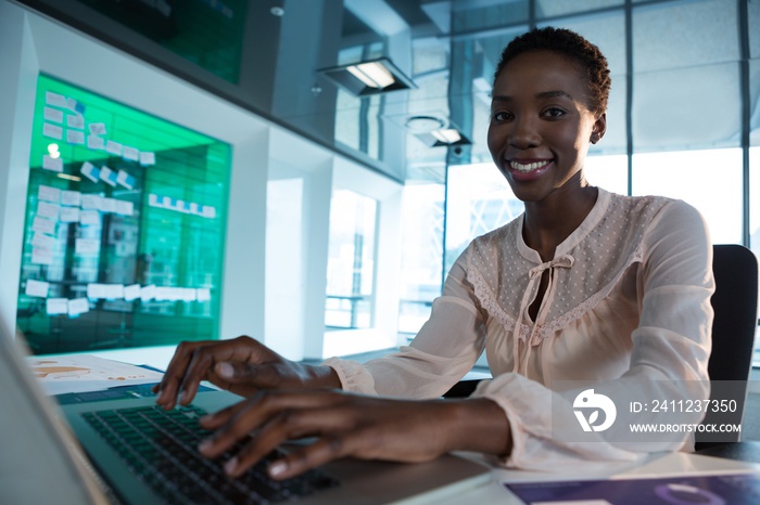 Female executive using laptop at desk