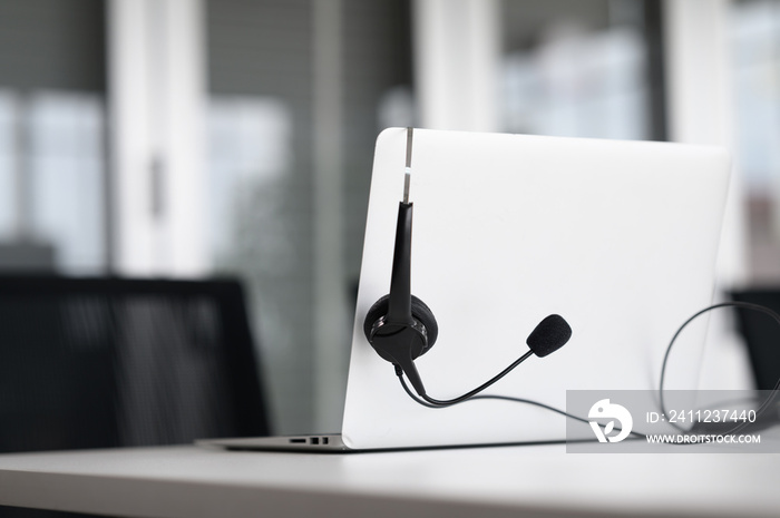 Headsets for call center teams are placed at a desk with a computer and laptop. while the team is in