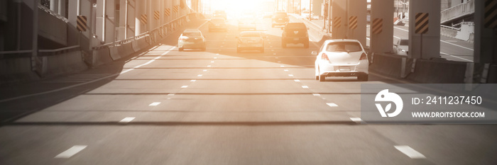 Cars on highway road at sunset evening in busy american city, heavy traffic moving at speed.