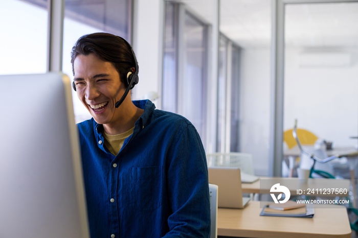 Male executive in headset working over computer at his desk