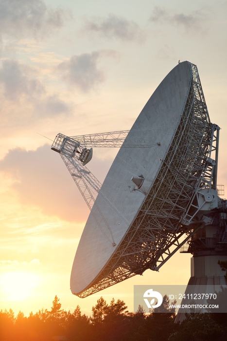 Large radio telescope. Dramatic sunset sky, glowing clouds. Nature, weather, science, equipment, tec