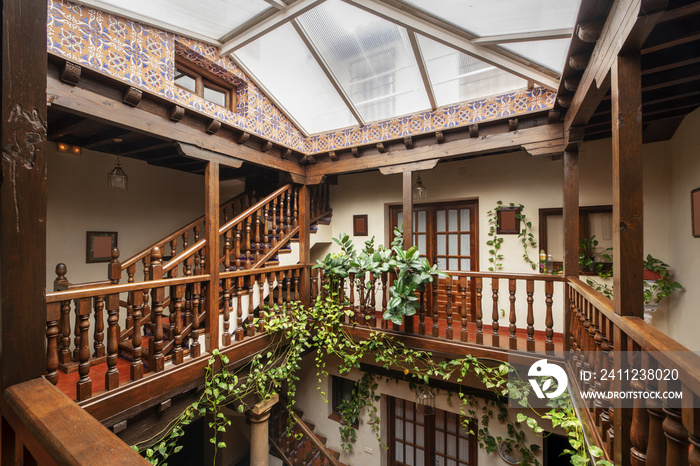 Atrium of an old house with wooden railings on the stairs and on the floors on wooden pillars and a 