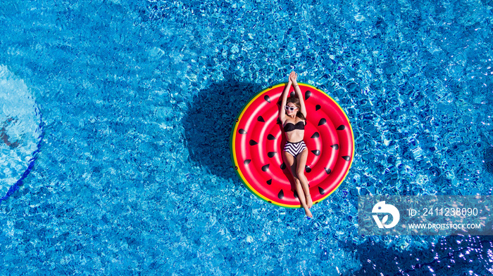 Young pretty woman relaxing on watermelon in pool floating with fruit mattress.