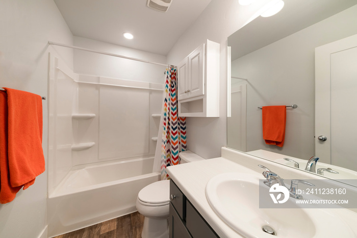 White bathroom with wall cabinet and colorful shower curtain